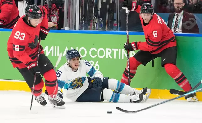 Finland's Teuvo Teravainen (86) challenges with Canada's Travis Sanheim (6) and Canada's Mitch Marner (93) during a men's ice hockey semifinal game between Canada and Finland at the 2026 Winter Olympics, in Milan, Italy, Friday, Feb. 20, 2026. (AP Photo/Hassan Ammar)