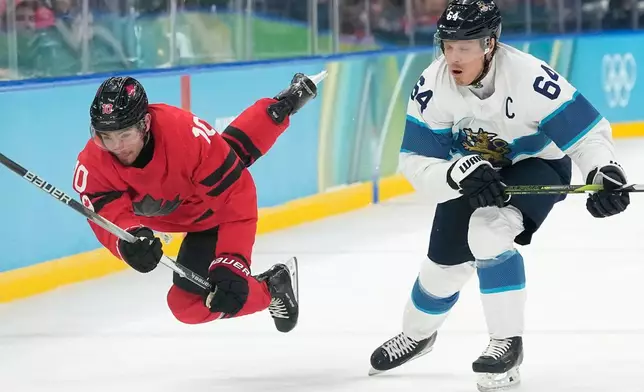 Canada's Nick Suzuki (10) challenges with Finland's Mikael Granlund (64) during a men's ice hockey semifinal game between Canada and Finland at the 2026 Winter Olympics, in Milan, Italy, Friday, Feb. 20, 2026. (AP Photo/Hassan Ammar)