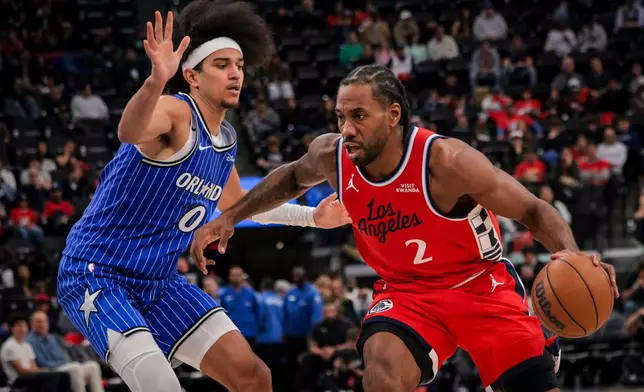 Los Angeles Clippers forward Kawhi Leonard, right, dribbles past Orlando Magic guard Anthony Black during the second half of a NBA basketball game, Sunday, Feb. 22, 2026, in Inglewood, Calif. (AP Photo/Etienne Laurent)