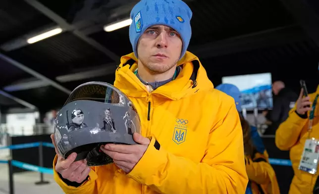 Ukrainian skeleton athlete Vladyslav Heraskevych holds his crash helmet as he stands in the mixed zone of the sliding center at the 2026 Winter Olympics, in Cortina d'Ampezzo, Italy, Thursday, Feb. 12, 2026. (AP Photo/Alessandra Tarantino)