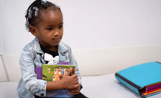 Juri Sleet, 4, holds a pair of books after completing a literacy screening at Linden Primary Care Center at Nationwide Children's Hospital, Thursday, Dec. 11, 2025, in Columbus, Ohio. (AP Photo/Jessica Phelps)