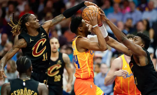 Charlotte Hornets forward Brandon Miller, center, drives to the basket against against Cleveland Cavaliers guard Keon Ellis (14) and center Thomas Bryant, right, during the first half of an NBA basketball game in Charlotte, N.C., Friday, Feb. 20, 2026. (AP Photo/Nell Redmond)