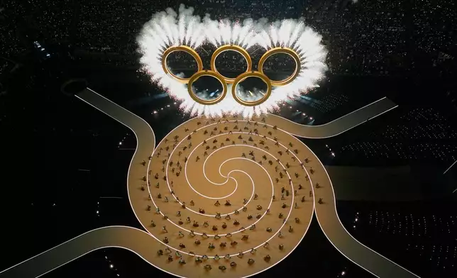 Entertainers perform under the Olympic rings during the Olympic opening ceremony at the 2026 Winter Olympics, in Milan, Italy, Friday, Feb. 6, 2026. (AP Photo/David J. Phillip)