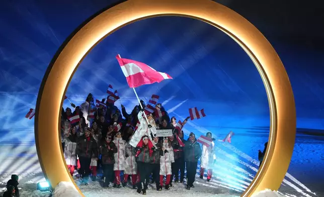 Benjamin Karl, bottom center, carries Anna Gasser, flag bearer of Austria, as they walk with athletes during the Olympic opening ceremony at the 2026 Winter Olympics, in Livigno, Italy, Friday, Feb. 6, 2026. (AP Photo/Lindsey Wasson)