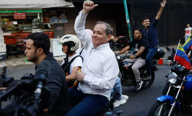 Opposition leader Juan Pablo Guanipa rides on the back of a motorcycle after his release from prison in Caracas, Venezuela, Sunday, Feb. 8, 2026. (AP Photo/Cristian Hernandez)