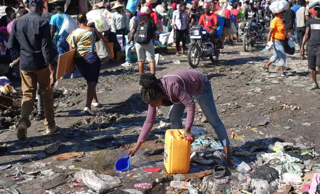 A woman collects water from a puddle in the Petion-Ville neighborhood of Port-au-Prince, Haiti, Wednesday, Feb. 11, 2026. (AP Photo/Odelyn Joseph)