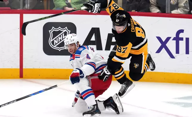 Pittsburgh Penguins' Sidney Crosby (87) leaps over New York Rangers' Braden Schneider (4) during the first period of an NHL hockey game in Pittsburgh, Saturday, Jan. 31, 2026. (AP Photo/Gene J. Puskar)