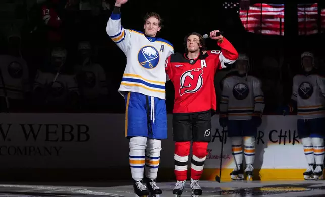 New Jersey Devils' Jack Hughes, right, and Buffalo Sabres' Tage Thompson gesture to fans before an NHL hockey game Wednesday, Feb. 25, 2026, in Newark, N.J. (AP Photo/Frank Franklin II)