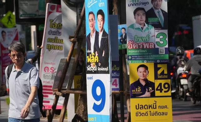 A man walks next to political parties' election campaign posters in Bangkok, Thailand, Wednesday, Feb. 4, 2026. (AP Photo/Sakchai Lalit)