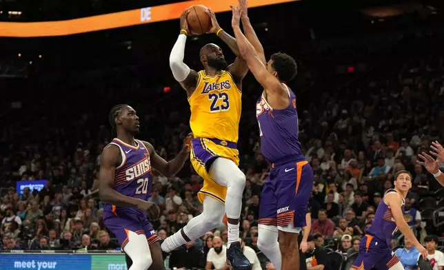 Los Angeles Lakers forward LeBron James drives between Phoenix Suns forward Rasheer Fleming (20) and forward Oso Ighodaro during the first half of an NBA basketball game, Thursday, Feb. 26, 2026, in Phoenix. (AP Photo/Rick Scuteri)