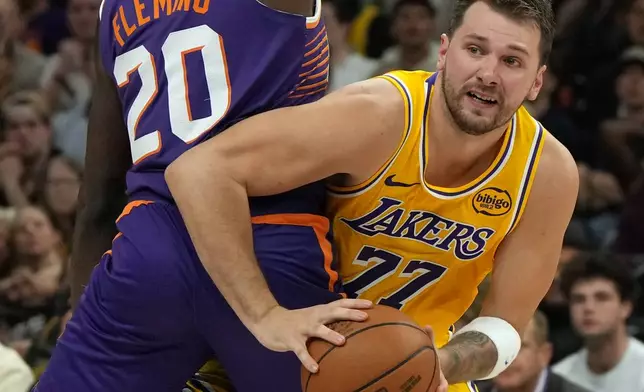 Los Angeles Lakers guard Luka Doncic looks to pass around Phoenix Suns forward Rasheer Fleming (20) during the first half of an NBA basketball game, Thursday, Feb. 26, 2026, in Phoenix. (AP Photo/Rick Scuteri)