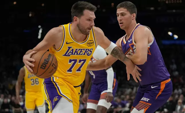Los Angeles Lakers guard Luka Doncic (77) shields the ball from Phoenix Suns guard Collin Gillespie during the first half of an NBA basketball game, Thursday, Feb. 26, 2026, in Phoenix. (AP Photo/Rick Scuteri)
