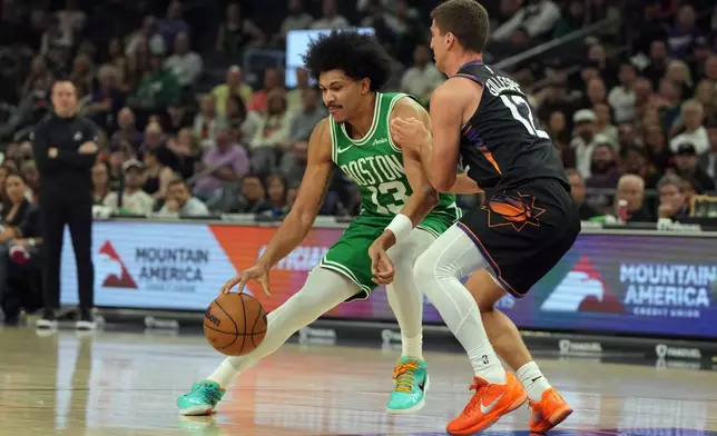 Boston Celtics guard Ron Harper Jr. drives on Phoenix Suns guard Collin Gillespie (12) during the first half of an NBA basketball game, Tuesday, Feb. 24, 2026, in Phoenix. (AP Photo/Rick Scuteri)