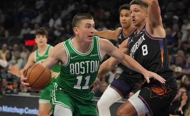 Boston Celtics guard Payton Pritchard (11) drives on Phoenix Suns guard Grayson Allen during the first half of an NBA basketball game, Tuesday, Feb. 24, 2026, in Phoenix. (AP Photo/Rick Scuteri)