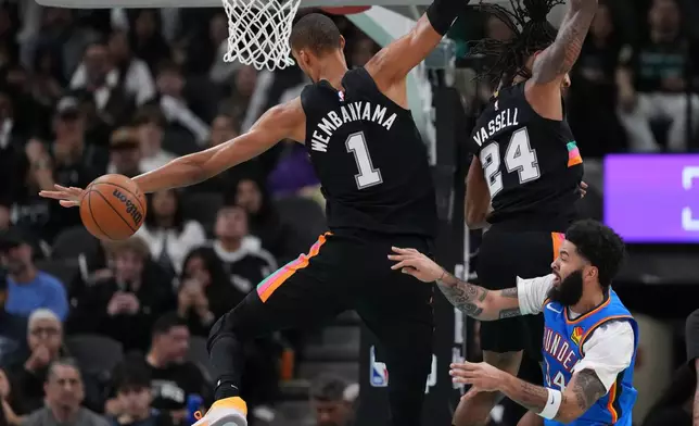 Oklahoma City Thunder guard Kenrich Williams (34) tries to move the ball past San Antonio Spurs forward Victor Wembanyama (1) and guard Devin Vassell (24) during the second half of an NBA basketball game in San Antonio, Wednesday, February. 4, 2026. (AP Photo/Eric Gay)