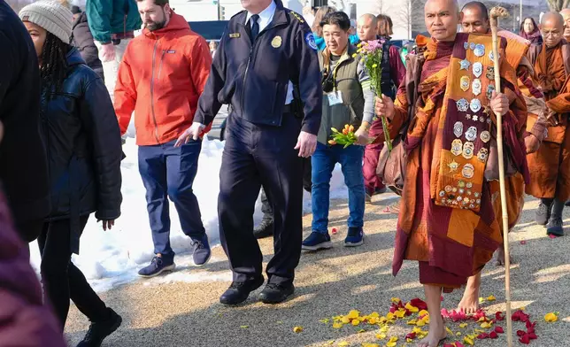 Bhikkhu Pannakara walks over flowers near the Peace Monument on Capitol Hill, during the Walk For Peace, Wednesday, Feb. 11, 2026, in Washington. (AP Photo/Mariam Zuhaib)
