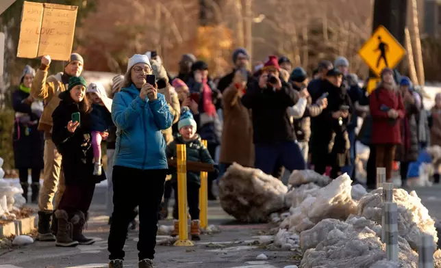 Spectators watch as Buddhist monks who are participating in a Walk For Peace walk through a neighborhood on Tuesday, Feb. 10, 2026, in Washington. (AP Photo/Mark Schiefelbein)