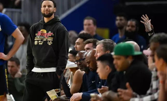 Golden State Warriors guard Stephen Curry stands by the team bench against the Philadelphia 76ers during the first half of an NBA basketball game Tuesday, Feb. 3, 2026, in San Francisco. (AP Photo/Eakin Howard)