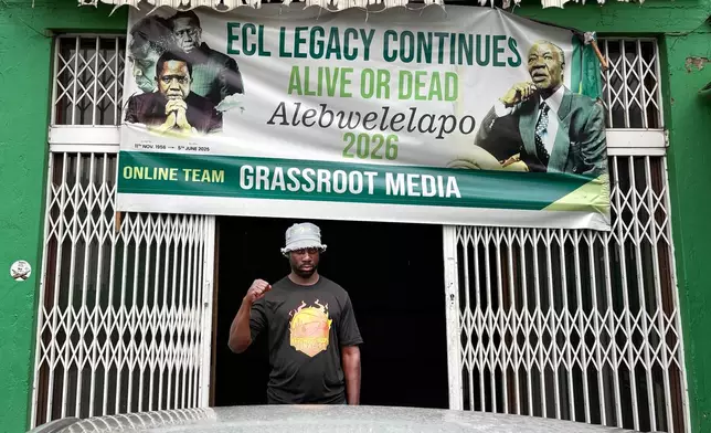 Richard Lungu, a supporter of former Zambian President Edgar Lungu, makes a power fist at the entrance to the headquarters of the opposition Patriotic Front party in Lusaka, Zambia, Thursday, Feb.12, 2026. (AP Photo/Rodney Muhumuza)
