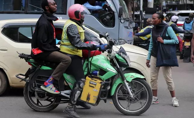 Men ride an electric Spiro motorcycle in Nairobi, Kenya, Tuesday, Feb. 24, 2026. (AP Photo/Henry Naminde)
