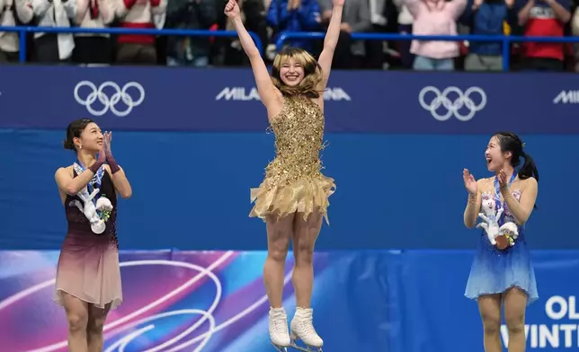 From left to right, silver medalist Kaori Sakamoto of Japan, gold medalist Alysa Liu of the United States, and bronze medalist Ami Nakai of Japan, jump on the podium to receive their medals after competing in the women's free skate program in figure skating at the 2026 Winter Olympics, in Milan, Italy, Thursday, Feb. 19, 2026. (AP Photo/Stephanie Scarbrough)