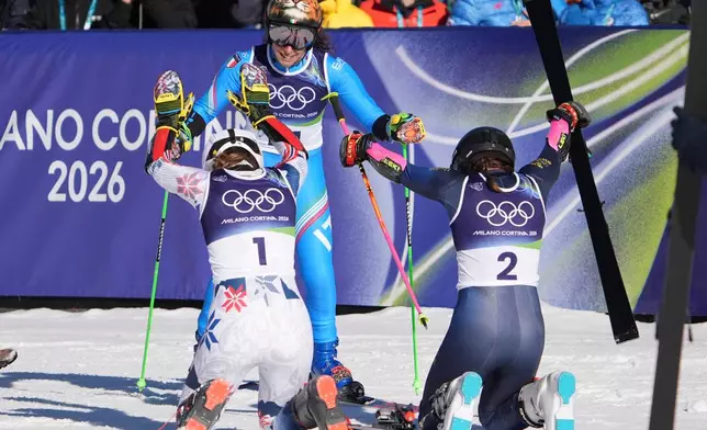 Sweden's Sara Hector, right, and Norway's Thea Louise Stjernesund bow to Italy's Federica Brignone, center, at the finish area of an alpine ski, women's giant slalom race, at the 2026 Winter Olympics, in Cortina d'Ampezzo, Italy, Sunday, Feb. 15, 2026. (AP Photo/Jacquelyn Martin)