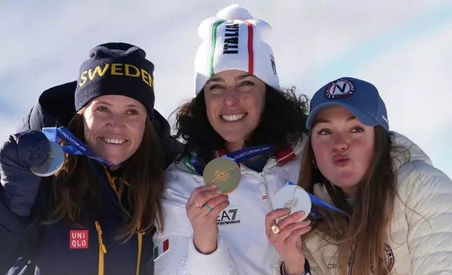 Italy's Federica Brignone, center, gold medalist in an alpine ski, women's giant slalom race, and joint silver medalists Sweden's Sara Hector, left, and Norway's Thea Louise Stjernesund, show their medals, at the 2026 Winter Olympics, in Cortina d'Ampezzo, Italy, Sunday, Feb. 15, 2026. (AP Photo/Jacquelyn Martin)