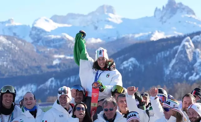 Italy's Federica Brignone, center, celebrates with members of the Italian team after winning the gold medal in an alpine ski, women's giant slalom race, at the 2026 Winter Olympics, in Cortina d'Ampezzo, Italy, Sunday, Feb. 15, 2026. (AP Photo/Jacquelyn Martin)