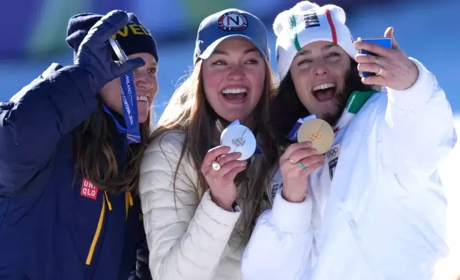 Italy's Federica Brignone, right, celebrates winning gold medal next to joint silver medalists Norway's Thea Louise Stjernesund and Sweden's Sara Hector, left, at the finish area of an alpine ski, women's giant slalom race, at the 2026 Winter Olympics, in Cortina d'Ampezzo, Italy, Sunday, Feb. 15, 2026.. (AP Photo/Robert F. Bukaty)