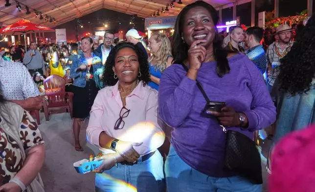 Friends enjoy a band performance during the Burger Bash at the South Beach Wine and Food Festival Friday, Feb. 20, 2026, in Miami Beach, Fla. (AP Photo/Marta Lavandier)