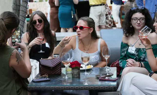 Tori Neville, center, and friends enjoy the food and drinks at the South Beach Wine and Food Festival Friday, Feb. 20, 2026, in Miami Beach, Fla. (AP Photo/Marta Lavandier)
