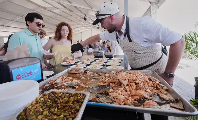 Chef Ryan O'Sullivan puts the finishing touches to samples of grilled Kvaroy salmon with fennel remoulade at the South Beach Wine and Food Festival Saturday, Feb. 21, 2026, in Miami Beach, Fla. (AP Photo/Marta Lavandier)