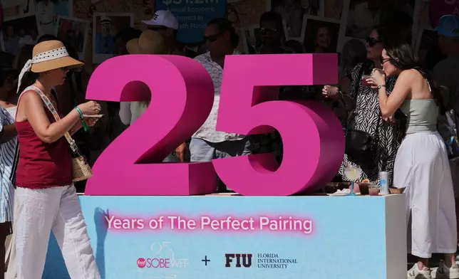 Attendees walk by the Florida International University 25th anniversary tent at the South Beach Wine and Food Festival Saturday, Feb. 21, 2026, in Miami Beach, Fla. (AP Photo/Marta Lavandier)