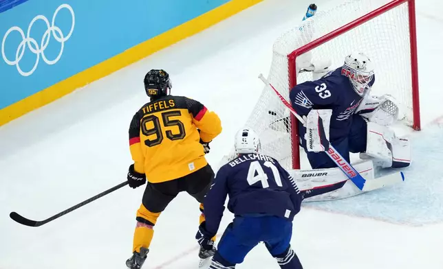 Germany's Frederik Tiffels (95) scores a goal against France goalkeeper Julian Junca (33) during the first period of a men's ice hockey qualification playoff game at the 2026 Winter Olympics, in Milan, Italy, Tuesday, Feb. 17, 2026. (AP Photo/Carolyn Kaster)