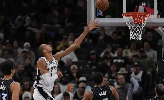 San Antonio Spurs forward Victor Wembanyama (1) scores over Orlando Magic guard Desmond Bane (3) during the first half of an NBA basketball game in San Antonio, Sunday, Feb. 1, 2026. (AP Photo/Eric Gay)