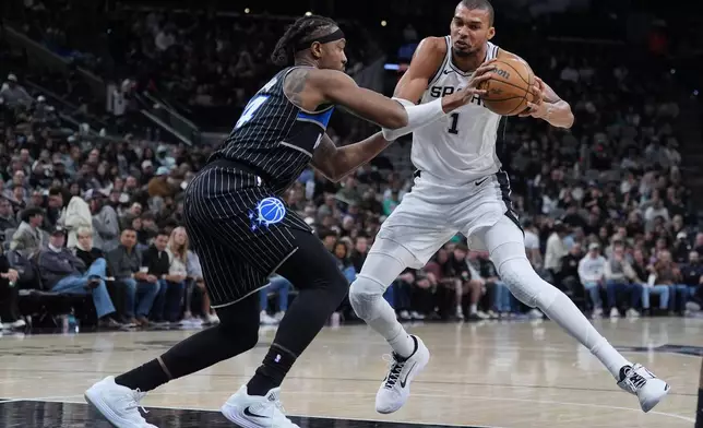 San Antonio Spurs forward Victor Wembanyama (1) drives against Orlando Magic center Wendell Carter Jr. (34) during the second half of an NBA basketball game in San Antonio, Sunday, Feb. 1, 2026. (AP Photo/Eric Gay)