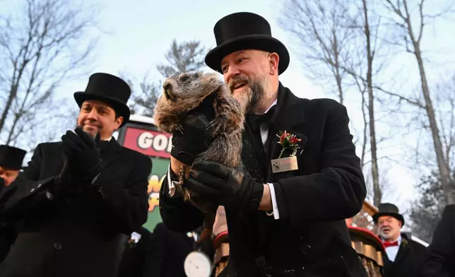 Groundhog Club handler A.J. Dereume holds Punxsutawney Phil, the weather prognosticating groundhog, during the 140th celebration of Groundhog Day on Gobbler's Knob in Punxsutawney, Pa., Monday, Feb. 2, 2026. Phil's handlers said that the groundhog has forecast six more weeks of winter. (AP Photo/Barry Reeger)
