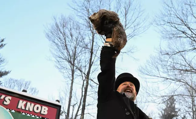 Groundhog Club handler A.J. Dereume holds Punxsutawney Phil, the weather prognosticating groundhog, during the 140th celebration of Groundhog Day on Gobbler's Knob in Punxsutawney, Pa., Monday, Feb. 2, 2026. Phil's handlers said that the groundhog has forecast six more weeks of winter. (AP Photo/Barry Reeger)