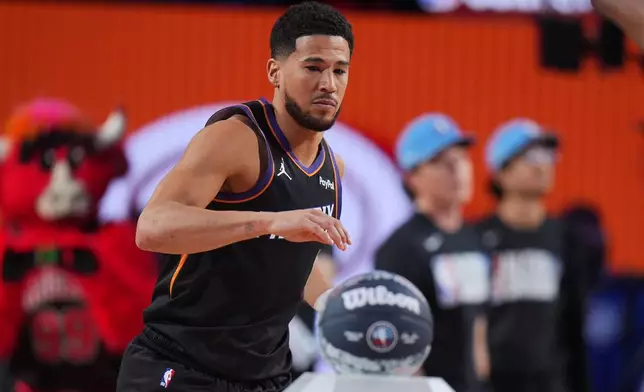 Phoenix Suns guard Devin Booker reaches for the ball during the 3-point contest at the NBA basketball All-Star weekend festivities Saturday, Feb. 14, 2026, in Inglewood, Calif. (AP Photo/Jae C. Hong)
