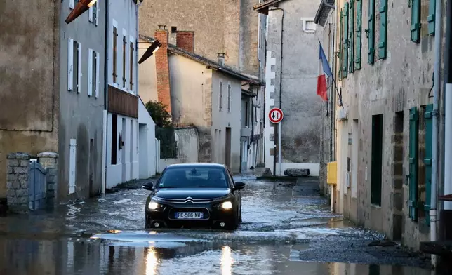 A car drives through a flooded street of Saint-Germain de Confolens as severe flooding hits western France amid storm Nils, Thursday, Feb. 12, 2026. (AP Photo/Yohan Bonnet)