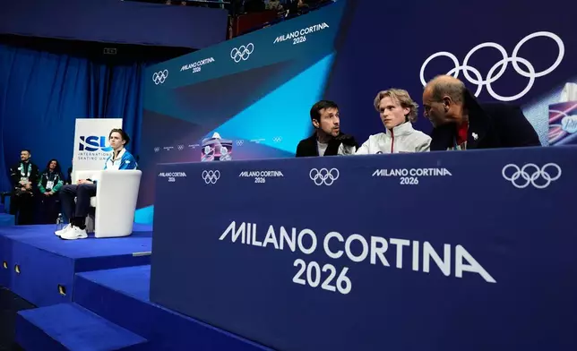 Ilia Malinin of the United States reacts after competing while Mikhail Shaidorov of Kazakhstan is seen on left while waiting for scores during the men's free skate program in figure skating at the 2026 Winter Olympics, in Milan, Italy, Friday, Feb. 13, 2026. (AP Photo/Ashley Landis)
