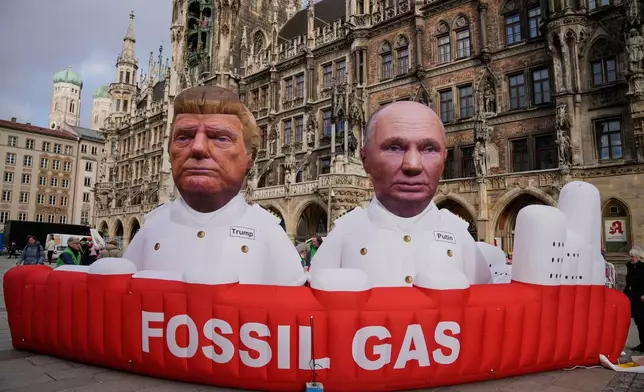 Figures depicting US President Donald Trump and Russian President Vladimir Putin, right, are displayed at Marienplatz square, as part of a protest against fossil energy by the environment organisation Greenpeace during the Munich Security Conference in Munich, Germany, Friday, Feb. 13, 2026. (AP Photo/Ebrahim Noroozi)