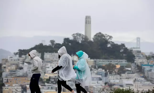 Visitors take in city views at Hyde and Lombard streets as rain begins to soak the Bay Area, in San Francisco, Sunday, Feb. 15, 2026. (Brontë Wittpenn/San Francisco Chronicle via AP)