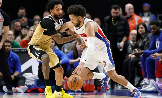 Detroit Pistons guard Cade Cunningham, right, drives against Washington Wizards forward Justin Champagnie during the first half of an NBA basketball game, Thursday, Feb. 5, 2026, in Detroit. (AP Photo/Duane Burleson)