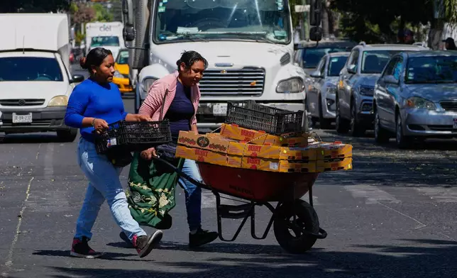 Fruit vendors walk along a street in Guadalajara, Mexico, on Tuesday, Feb. 24, 2026. (AP Photo/Marco Ugarte)