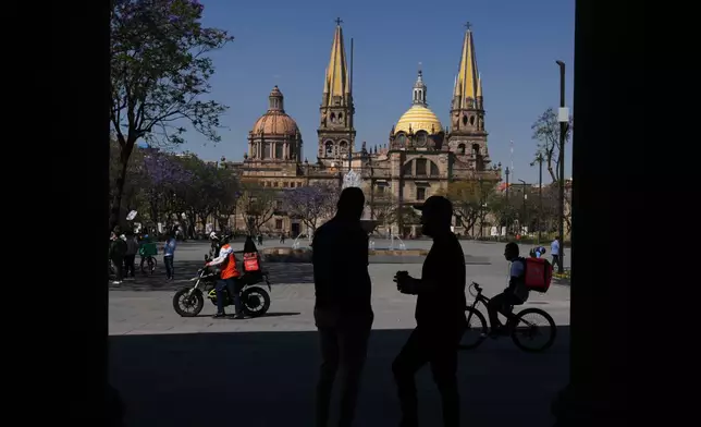 People mill about in the plaza of the Cathedral of the Assumption of Our Lady in the center of Guadalajara, Mexico, Wednesday, Feb. 25, 2026. (AP Photo/Marco Ugarte