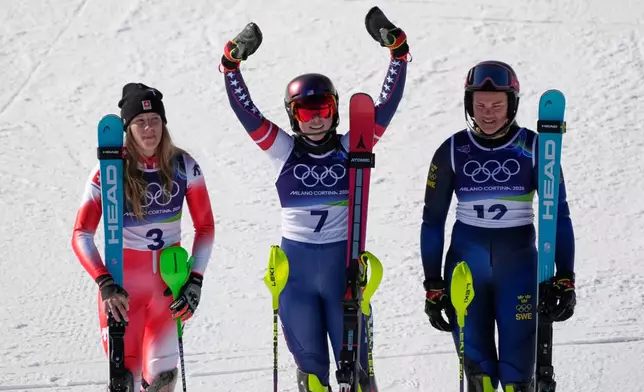 United States' Mikaela Shiffrin, center, winner of an alpine ski, women's slalom race, celebrates with second-placed Switzerland's Camille Rast, left, and third-placed Sweden's Anna Swenn Larsson, at the 2026 Winter Olympics, in Cortina d'Ampezzo, Italy, Wednesday, Feb. 18, 2026. (AP Photo/Andy Wong)