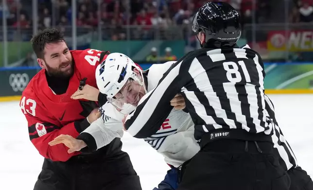 Canada's Tom Wilson (43) and France's Pierre Crinon, center, fight in the third period during a preliminary round game of men's ice hockey between Canada and France at the 2026 Winter Olympics, in Milan, Italy, Sunday, Feb. 15, 2026. (Nathan Denette/The Canadian Press via AP)