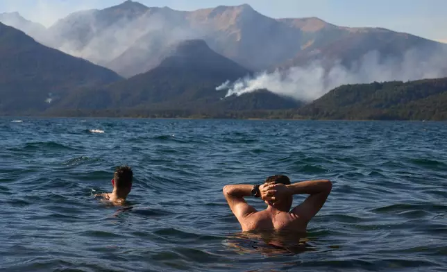 Firefighters relax by Futalaufquen Lake after battling wildfires in Los Alerces National Park, Argentina, Saturday, Jan. 31, 2026. (AP Photo/Victor R. Caivano)