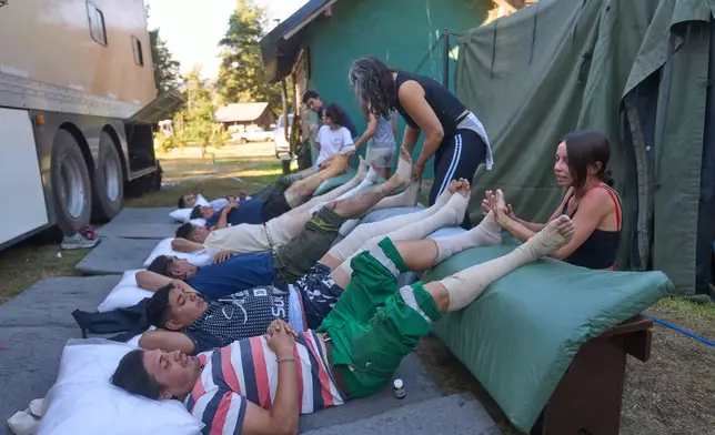 Volunteers massage firefighters resting after battling wildfires in Los Alerces National Park, Argentina, Saturday, Jan. 31, 2026. (AP Photo/Victor R. Caivano)